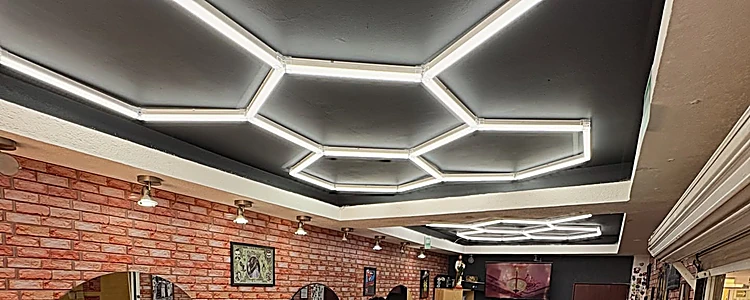Techo negro con hexágonos de luz LED blanca sobre el muro de ladrillo rojo